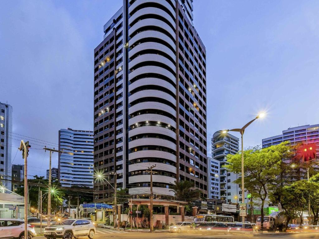 フォルタレザにあるMercure Fortaleza Meirelesの街中に駐車された車のある高層ビル