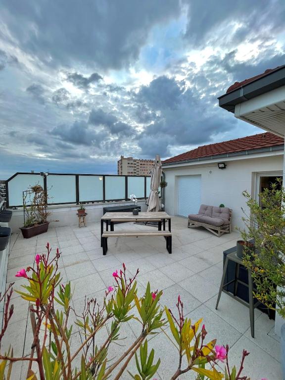 a patio with a table and a bench on a roof at Superbe appart design - Rooftop privé proche Paris in Neuilly-sur-Marne