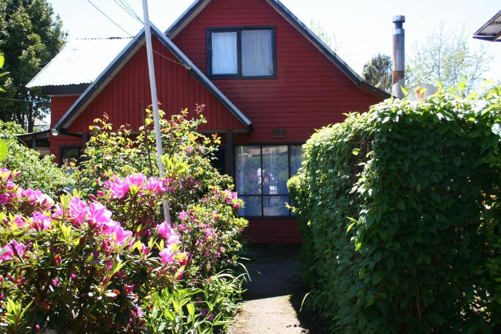 a red house with some flowers in front of it at Pucón Forest Wellness in Pucón