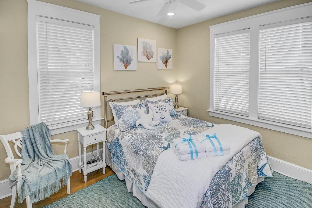 una camera da letto con un letto, una sedia e finestre di Almost Heaven in Watersound Proper INCLUDES Carriage House! Bedding for 12 a Rosemary Beach