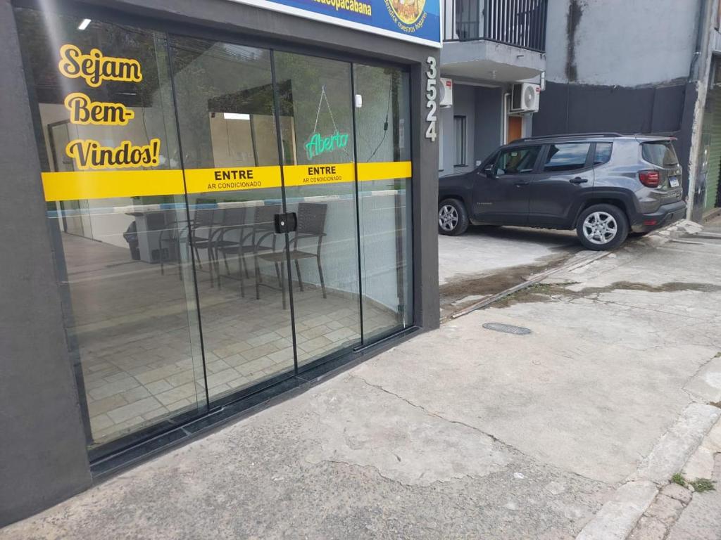 a car parked in front of a building with glass windows at Pousada Nossa Senhora de Copacabana in Aparecida