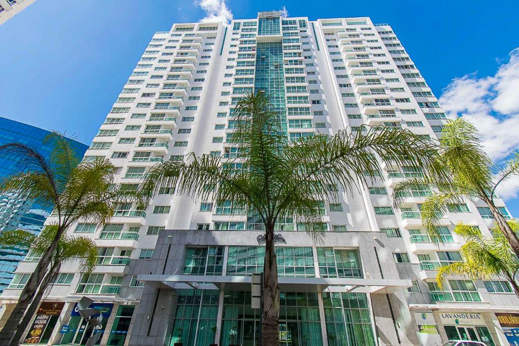 a tall white building with palm trees in front of it at Saint Moritz Hotel em Brasília 63873 in Brasilia