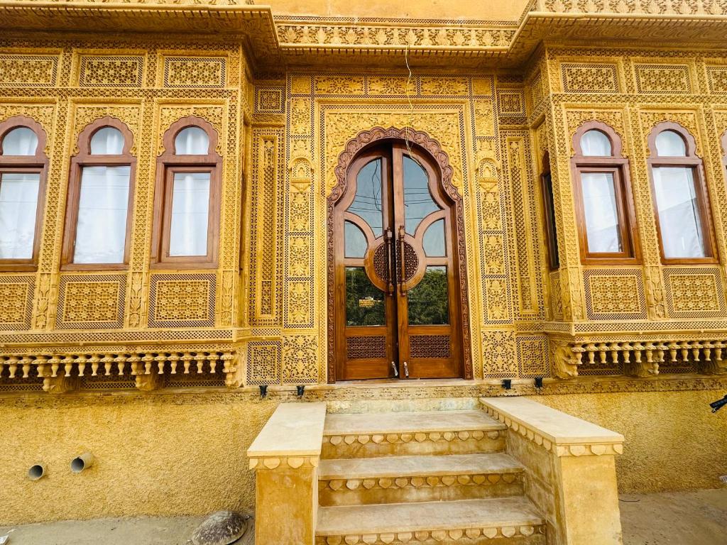 ジャイサルメールにあるHotel Golden Safariの木製のドアと階段が正面にある建物
