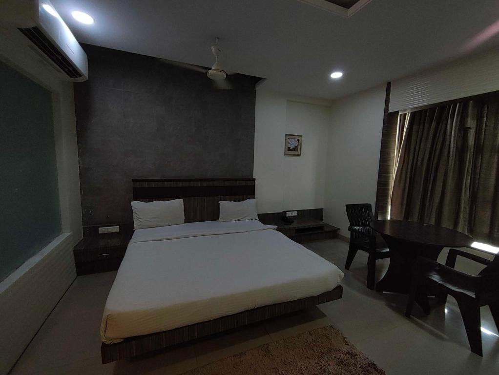a bedroom with a white bed and a table and chairs at Collection O Aurangabad Central Bus Terminal in Aurangabad