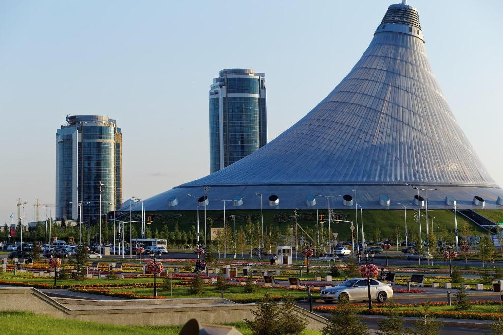 a large building with two tall buildings in the background at Apartments on Khan Shatyr in Astana
