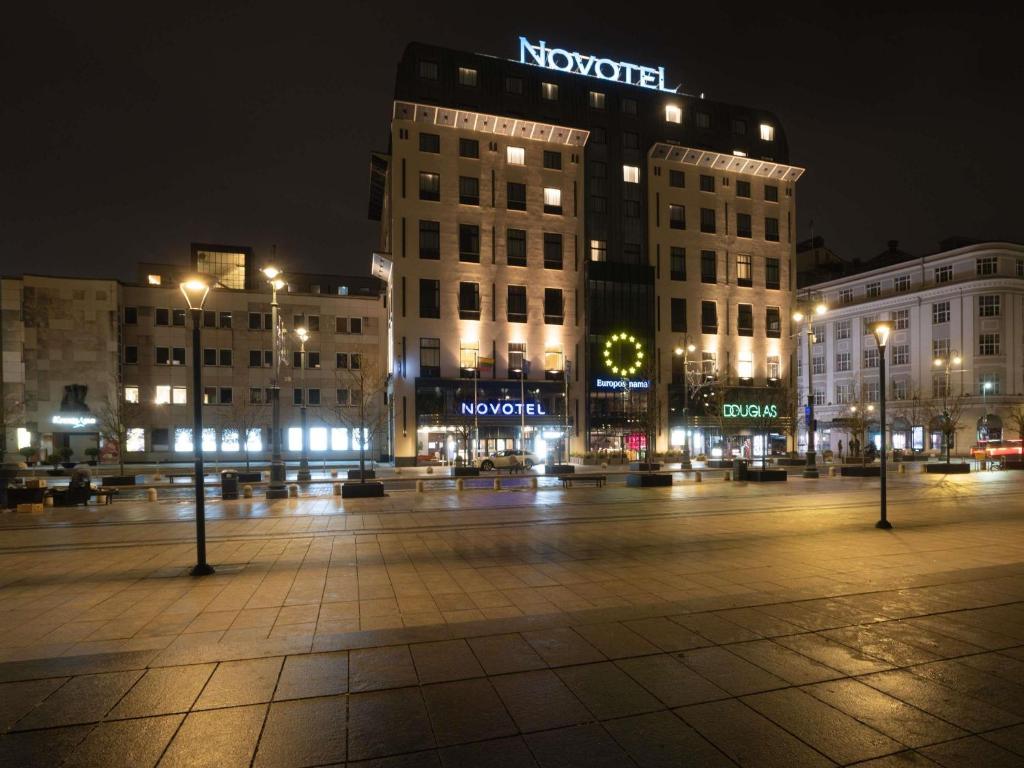 a city square at night with buildings and lights at Novotel Vilnius Centre in Vilnius