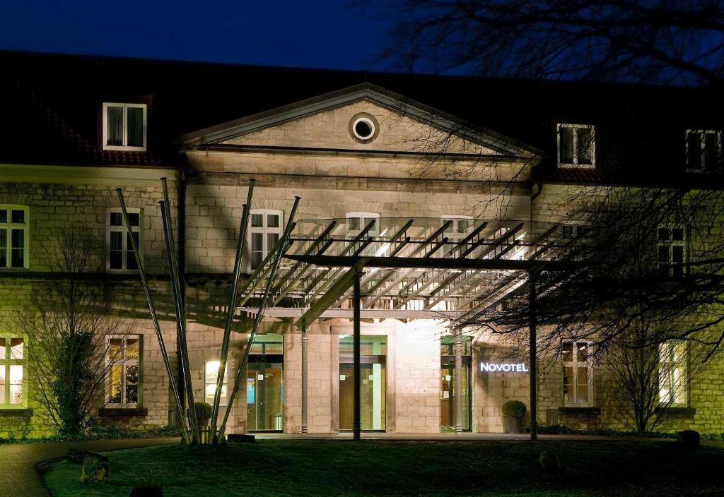 a building with a lit up front of it at night at Novotel Hildesheim in Hildesheim