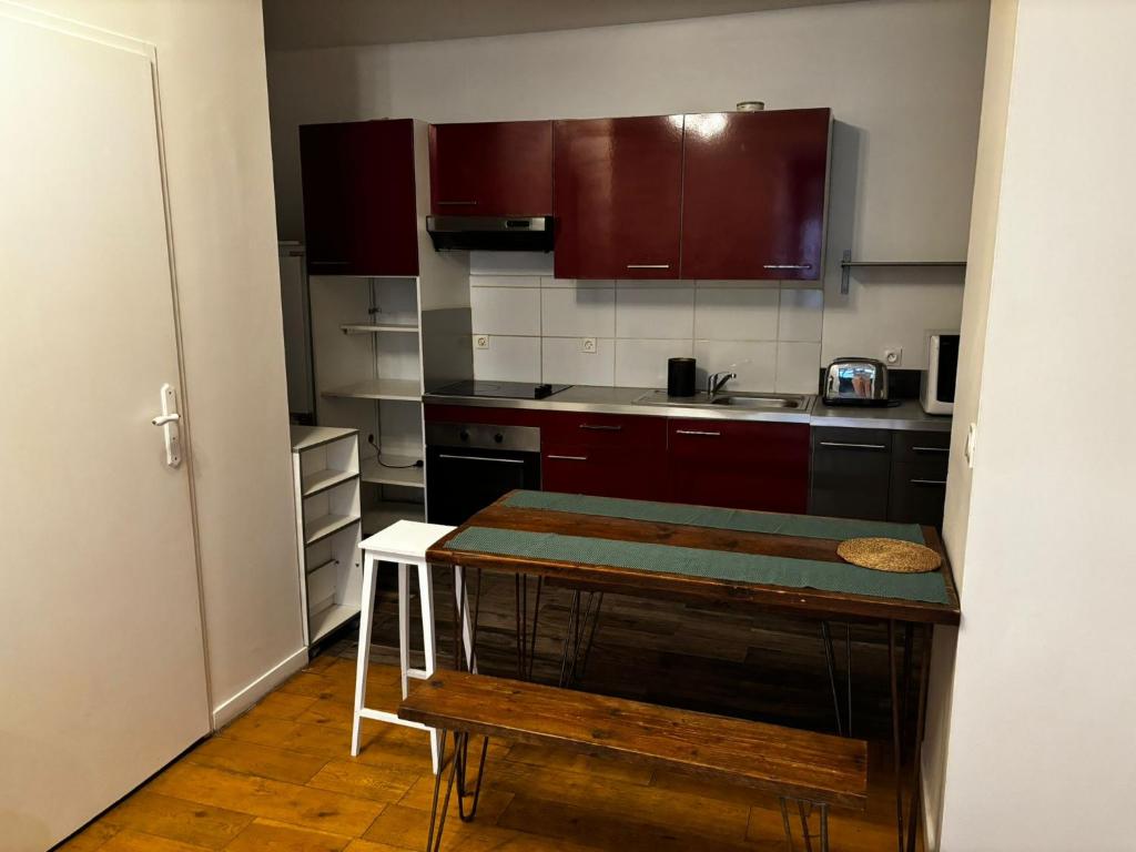a kitchen with red cabinets and a table in it at Appartement Victoire in Bordeaux