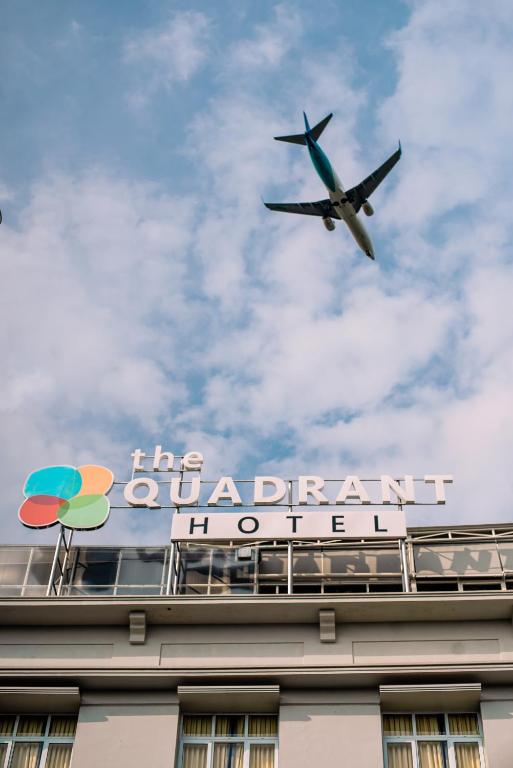 an airplane is flying over a building with a sign at The Quadrant Hotel KNO in Medan