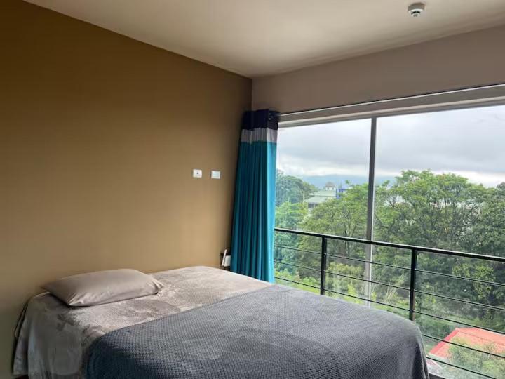 a bedroom with a bed and a large window at Daitares Home in San Pedro
