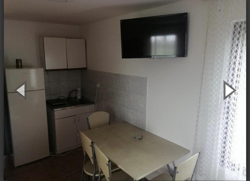 a small kitchen with a table and a refrigerator at Apartmani Da-Da in Gornji Milanovac