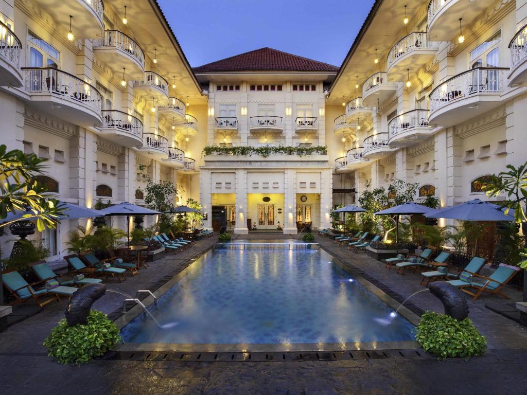 a large building with a swimming pool in the middle at The Phoenix Hotel Yogyakarta - Handwritten Collection in Yogyakarta