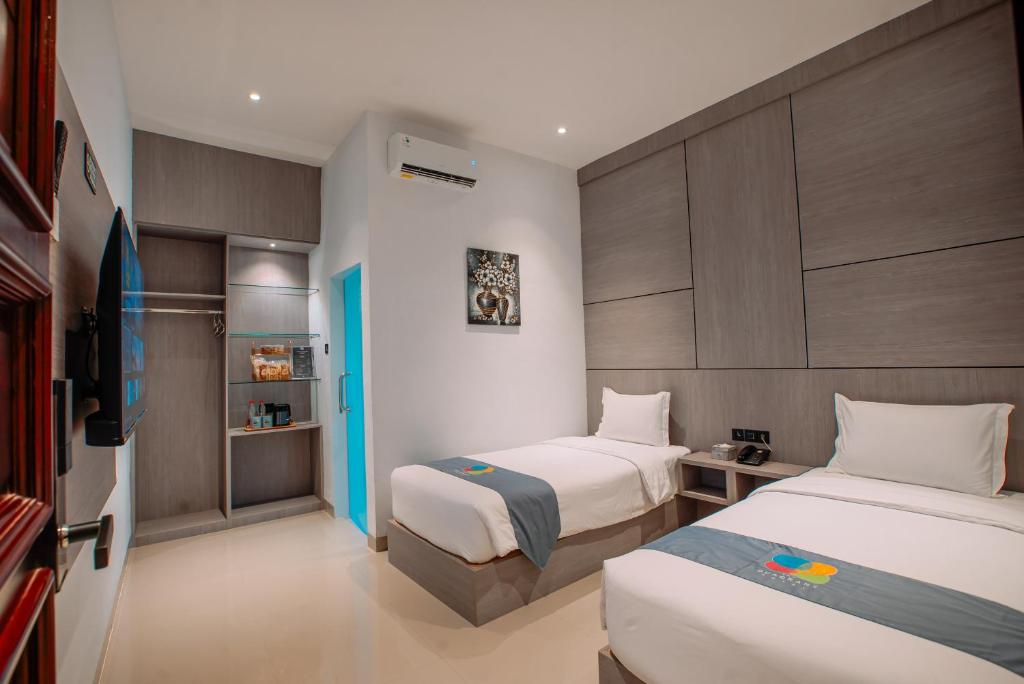 a hotel room with two beds and a tv at The Quadrant Hotel KNO in Medan