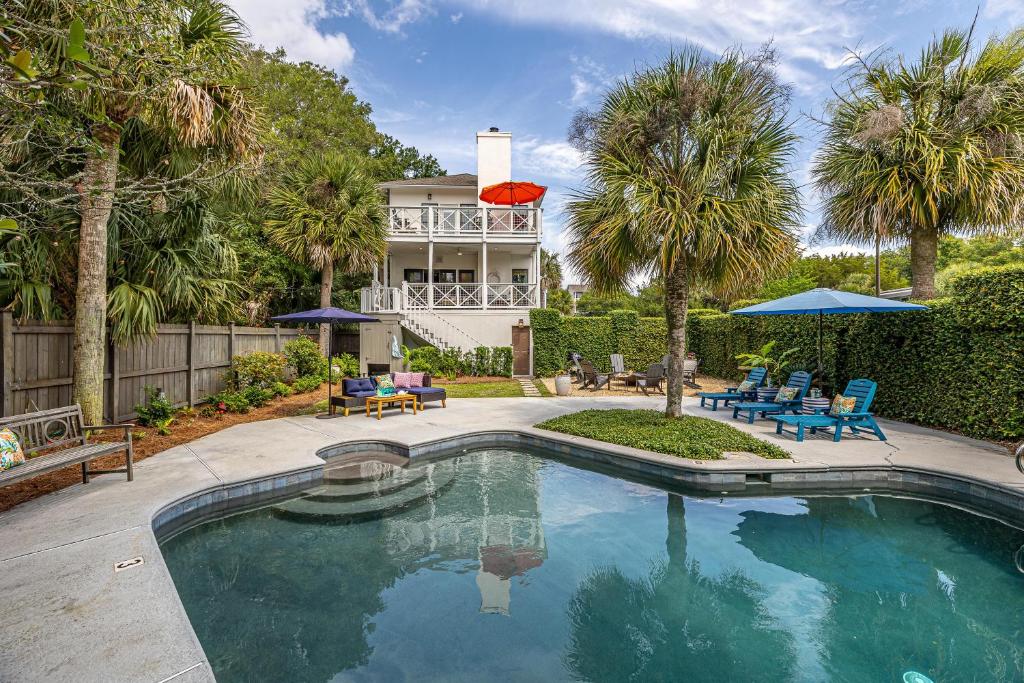 a swimming pool in front of a house with palm trees at 225 Olive Way in East End
