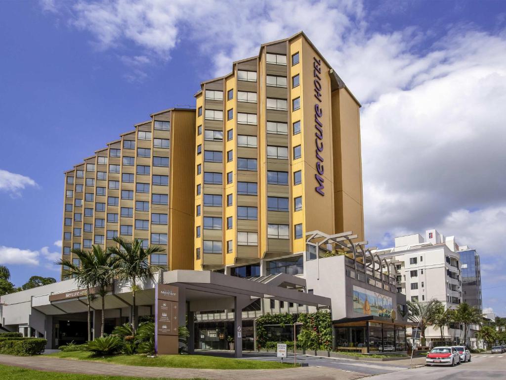 a tall yellow building with a parking lot at Mercure Florianópolis in Florianópolis