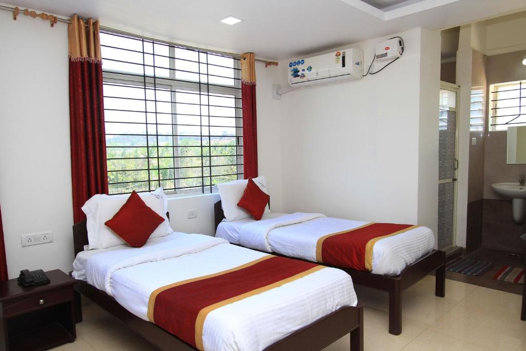 a hotel room with two beds and a window at Hotel O Sri Sai Residency in Bidadi