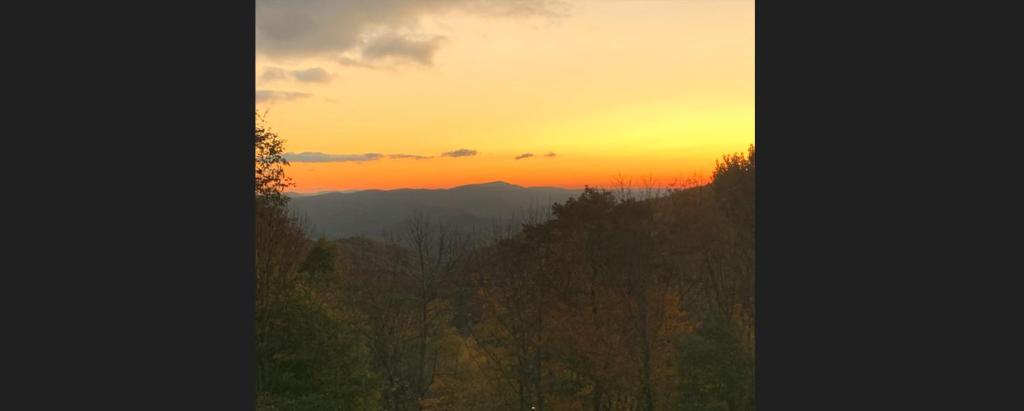 a sunset in the mountains with trees in the foreground at Seven Devils Sunrise in Seven Devils
