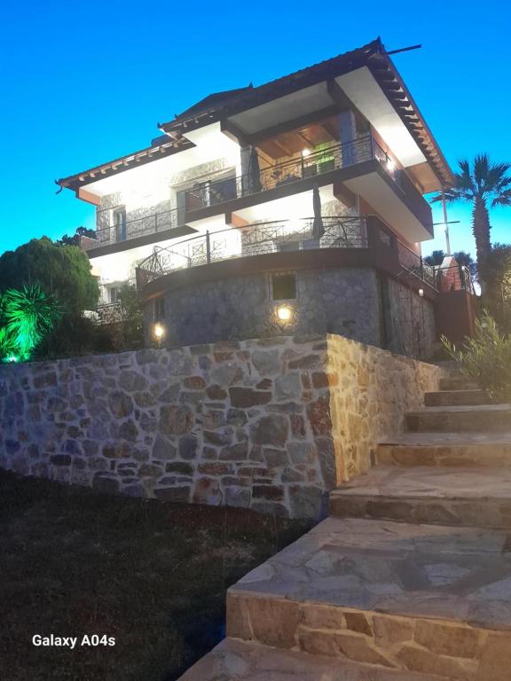 a house with a stone wall and stairs at night at Villa Nestor in Platamonas