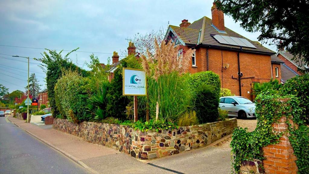 a sign in front of a house on a street at Coastal Lodge in Leiston