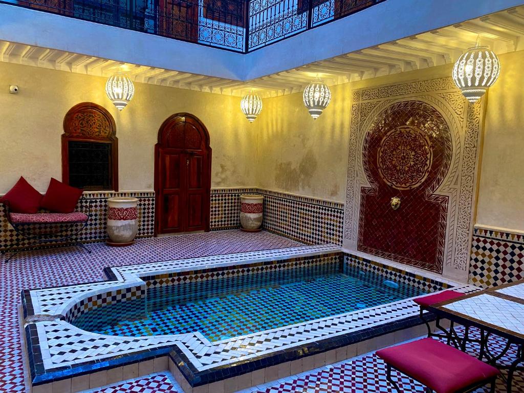 a swimming pool in a building with a table and chairs at Riad Prada in Marrakech