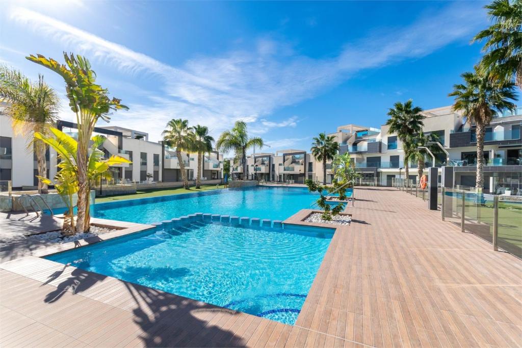 a swimming pool at a resort with palm trees and buildings at Apartment in Guardamar del Segura, Oasis Beach X in Guardamar del Segura