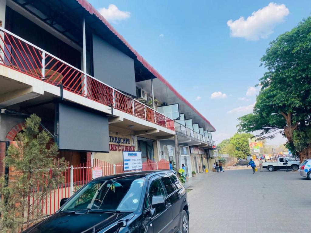 Un coche negro aparcado delante de un edificio en Starscape Lodge, en Ndola