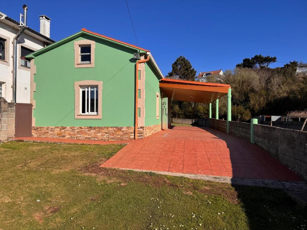 a green house with a brick driveway at La Casita de Toñita in Valdoviño