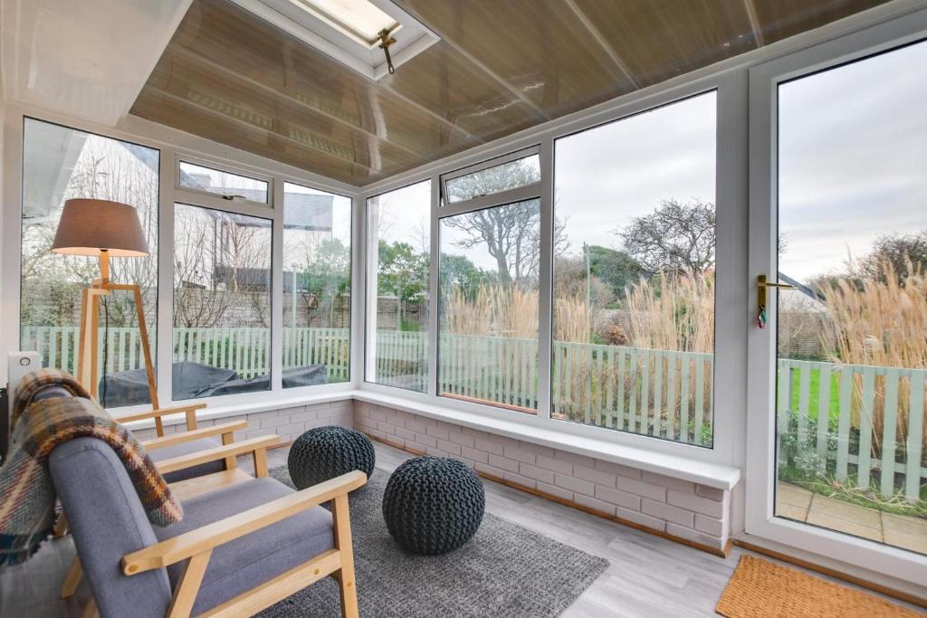 a screened in porch with windows and a couch at Murmur Y Llanw in Port-Eynon