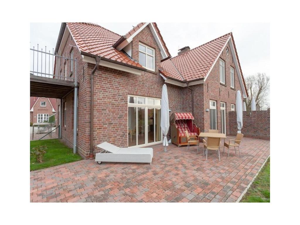 een stenen huis met een patio met een tafel en stoelen bij Suurhusen - Greetsiel in Greetsiel