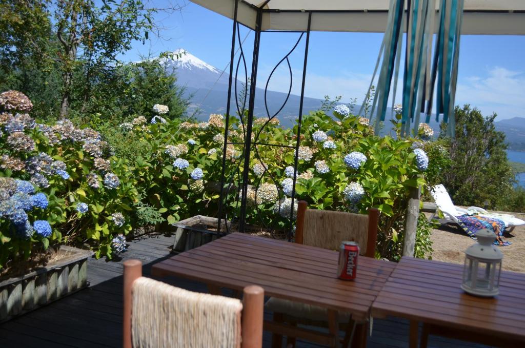 una mesa de madera y sillas en una terraza con flores en Casa Pucón Vista Lago y Volcan, en Pucón