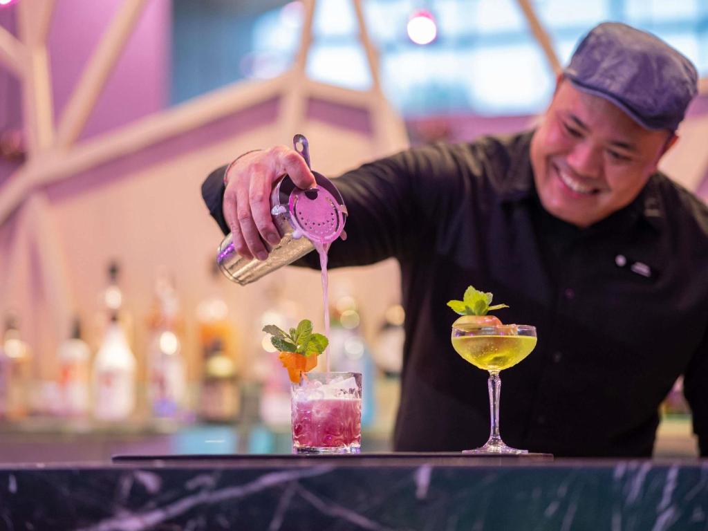 a man is pouring a drink into a cocktail at Pullman Bali Legian Beach in Legian