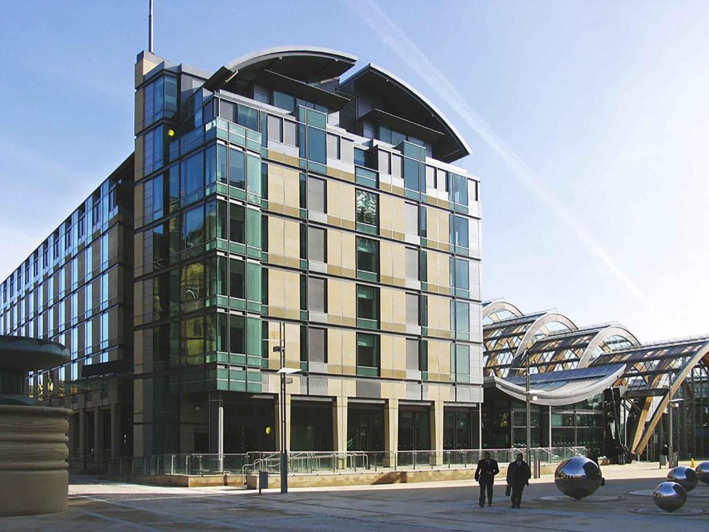 un gran edificio de cristal con gente de pie delante de él en Mercure Sheffield St Paul's Hotel & Spa, en Sheffield