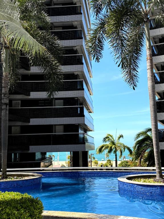 a swimming pool in front of a building with palm trees at Landscape Beira-Mar Perfect in Fortaleza