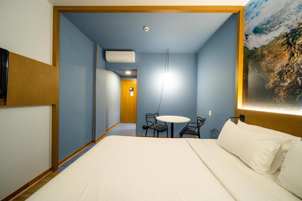 a bedroom with a large bed and a table at Hotel Euro Suite Curitiba Batel By Nacional Inn in Curitiba