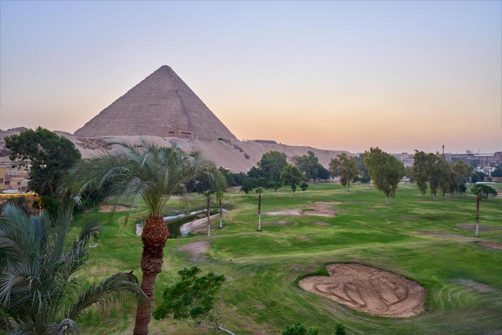 a view of the pyramids of egypt with palm trees at Beit Khufu Pyramid Hotel in Cairo