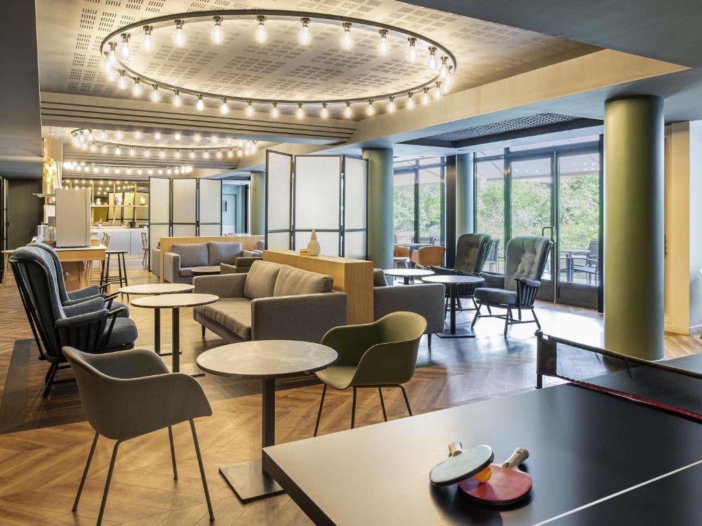 a hotel lobby with tables and chairs and a chandelier at Aparthotel Adagio Porte de Versailles in Issy-les-Moulineaux