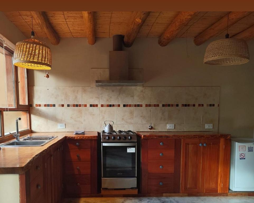 Una cocina con gabinetes de madera y un horno de estufa. en Juella cabaña, en Tilcara
