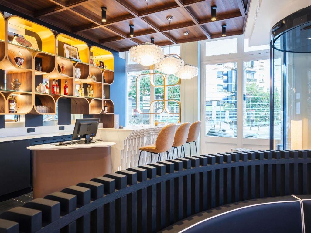 a restaurant with a bar with chairs and a counter at Grand Hotel des Brotteaux Lyon Ctre - Handwritten Collection in Lyon