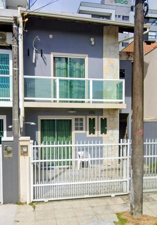 una casa con una valla blanca delante en Sobrado vista mar Piçarras, en Piçarras