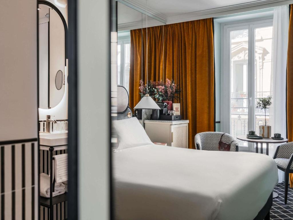 a hotel room with a bed and a bathroom at Hotel Faubourg Galant Paris - Handwritten Collection in Paris