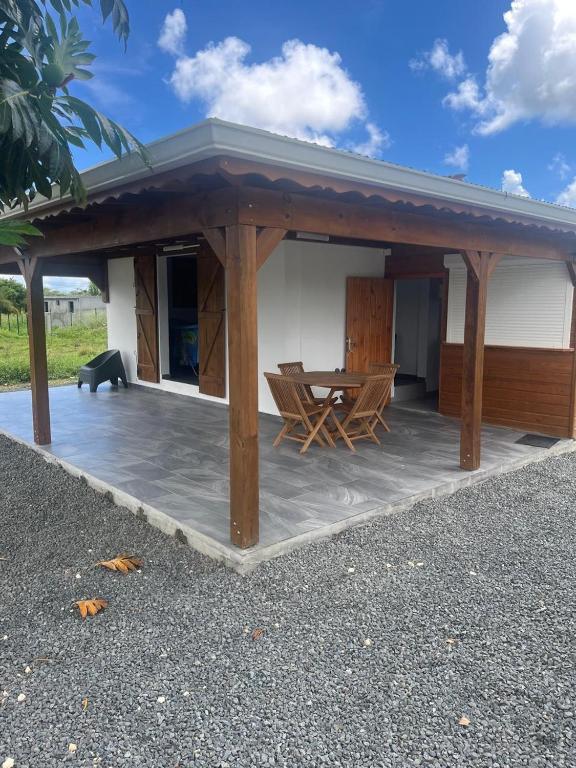 a wooden pavilion with a table and a bench at Le gîte de Chris in Sainte-Anne