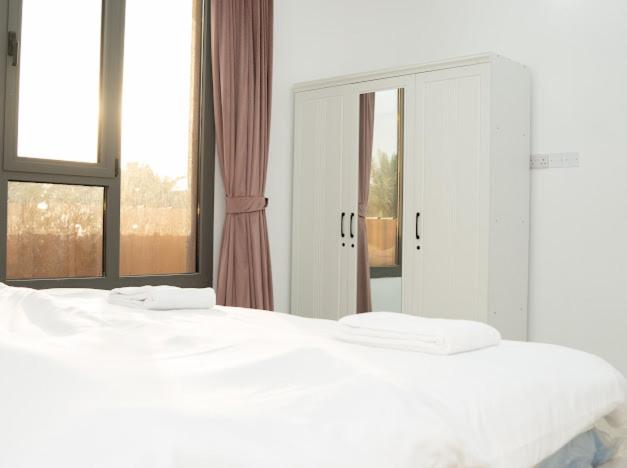 a bedroom with two white beds and a mirror at استراحة روضة الوادي - Rawdat Al Wadi House in Nizwa