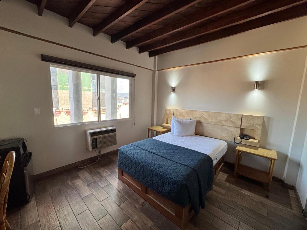 a bedroom with a bed and a large window at Hotel Paris in Tijuana