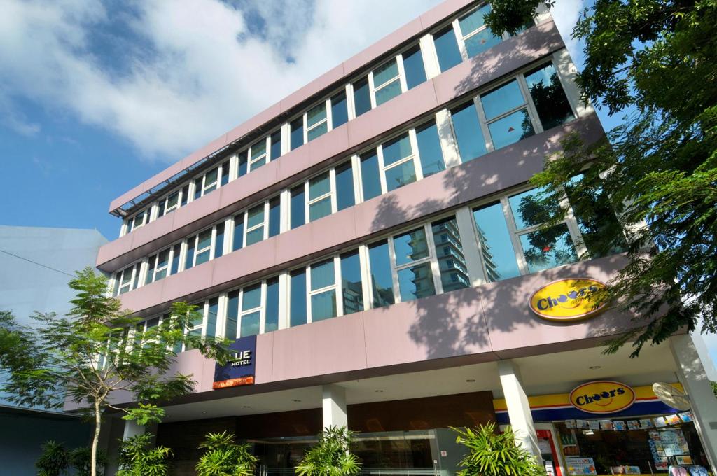 un bâtiment rose avec un panneau jaune dans l'établissement Value Hotel Balestier, à Singapour