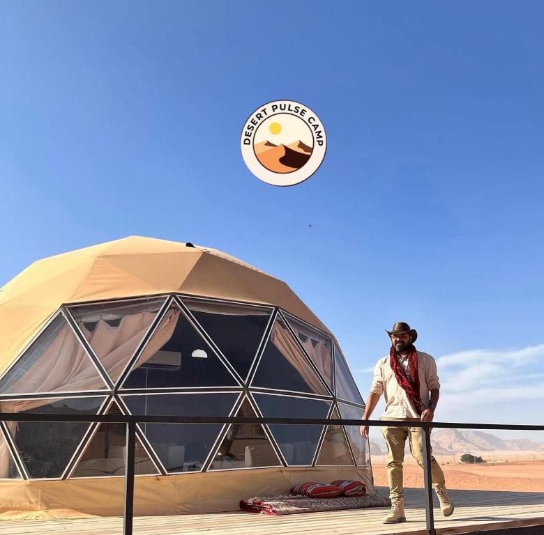 a man standing next to a tent in the desert at RUM BULSE BUBBLE lUXURY CAMP in Disah