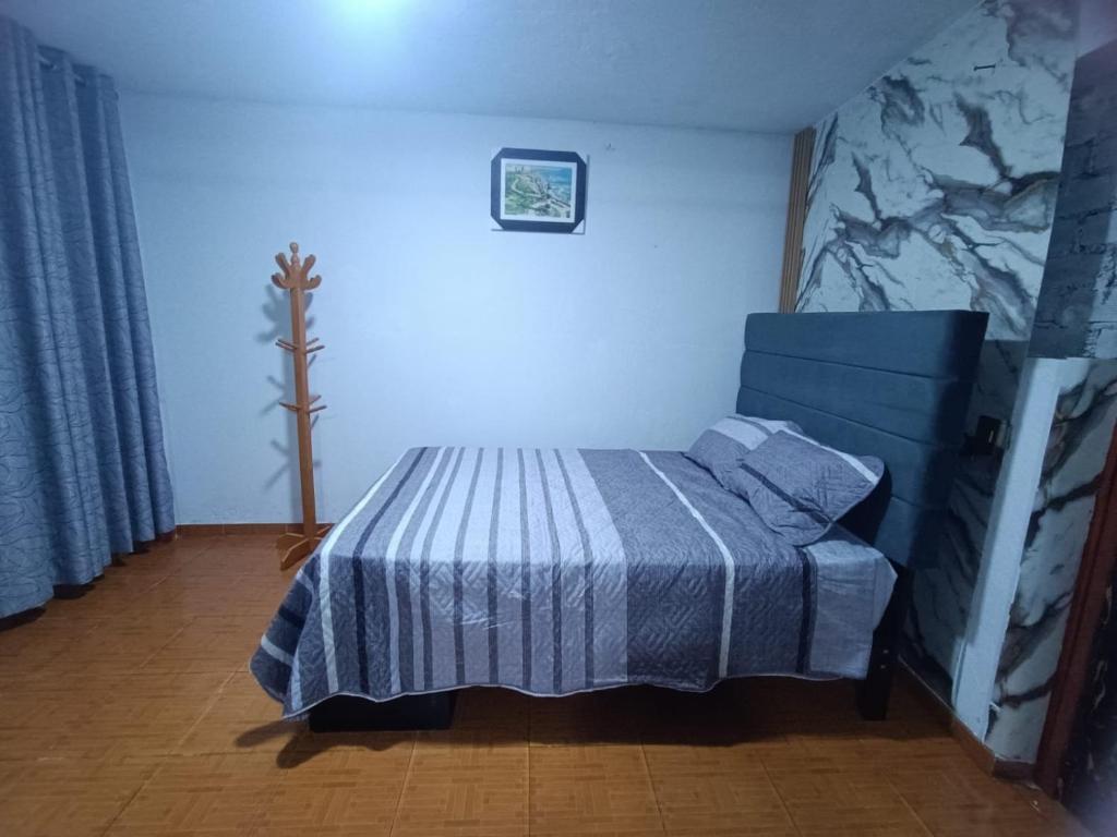 a bedroom with a bed with a blue and white blanket at Hospedaje - A y C Taxi- Airport - Accommodation in Lima