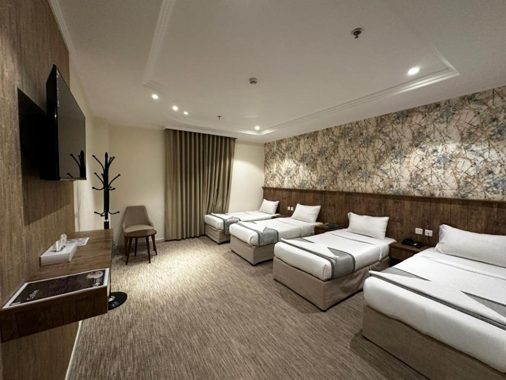 a hotel room with three beds and a television at الخلفاء الماسى in Makkah