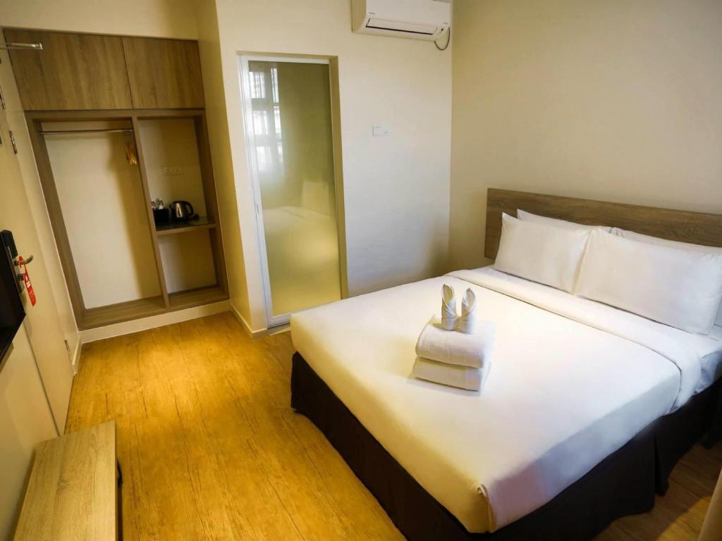 a hotel room with a large bed with two shoes on it at Rooms By Rocana in Kuantan