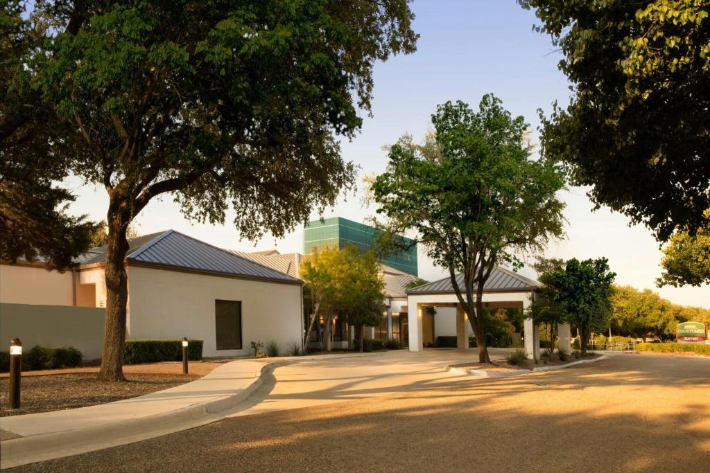an empty street in front of a building with trees at Courtyard Dallas Las Colinas in Irving