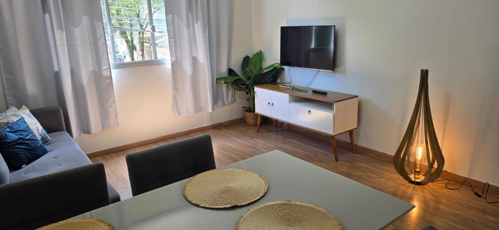 un soggiorno con un tavolo e una tv di Dois quartos espaçoso a Vitória